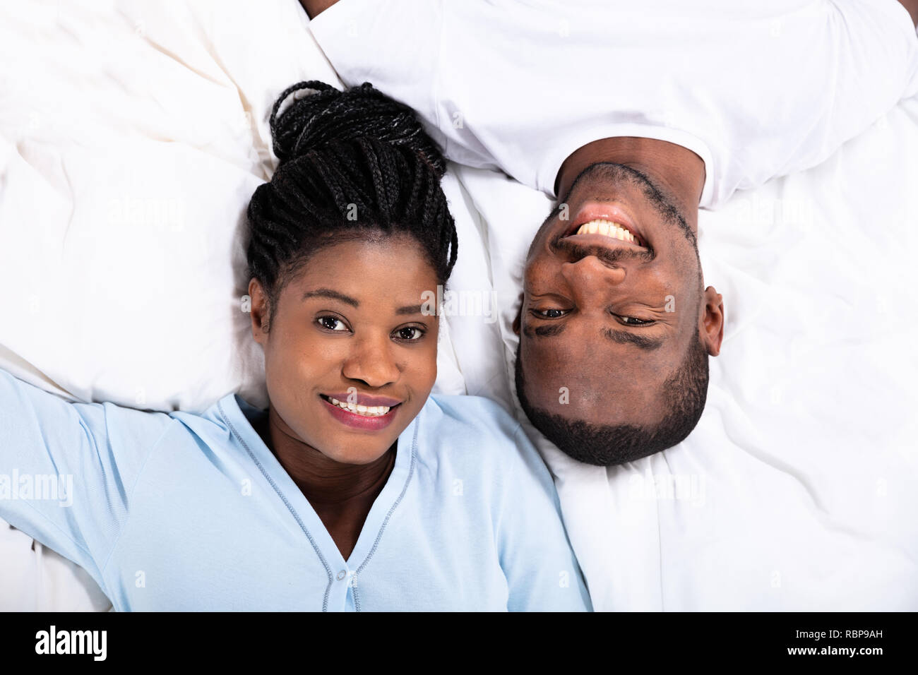 High Angle View Of Happy African Couple Lying On Bed Stock Photo
