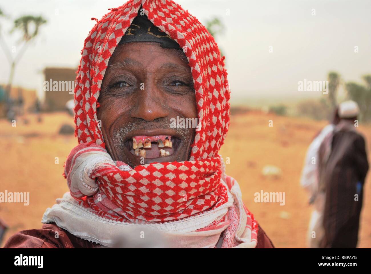 A smiling, old Fulani man with missing teeth happy to have visitors in his village in Niger, Africa Stock Photo