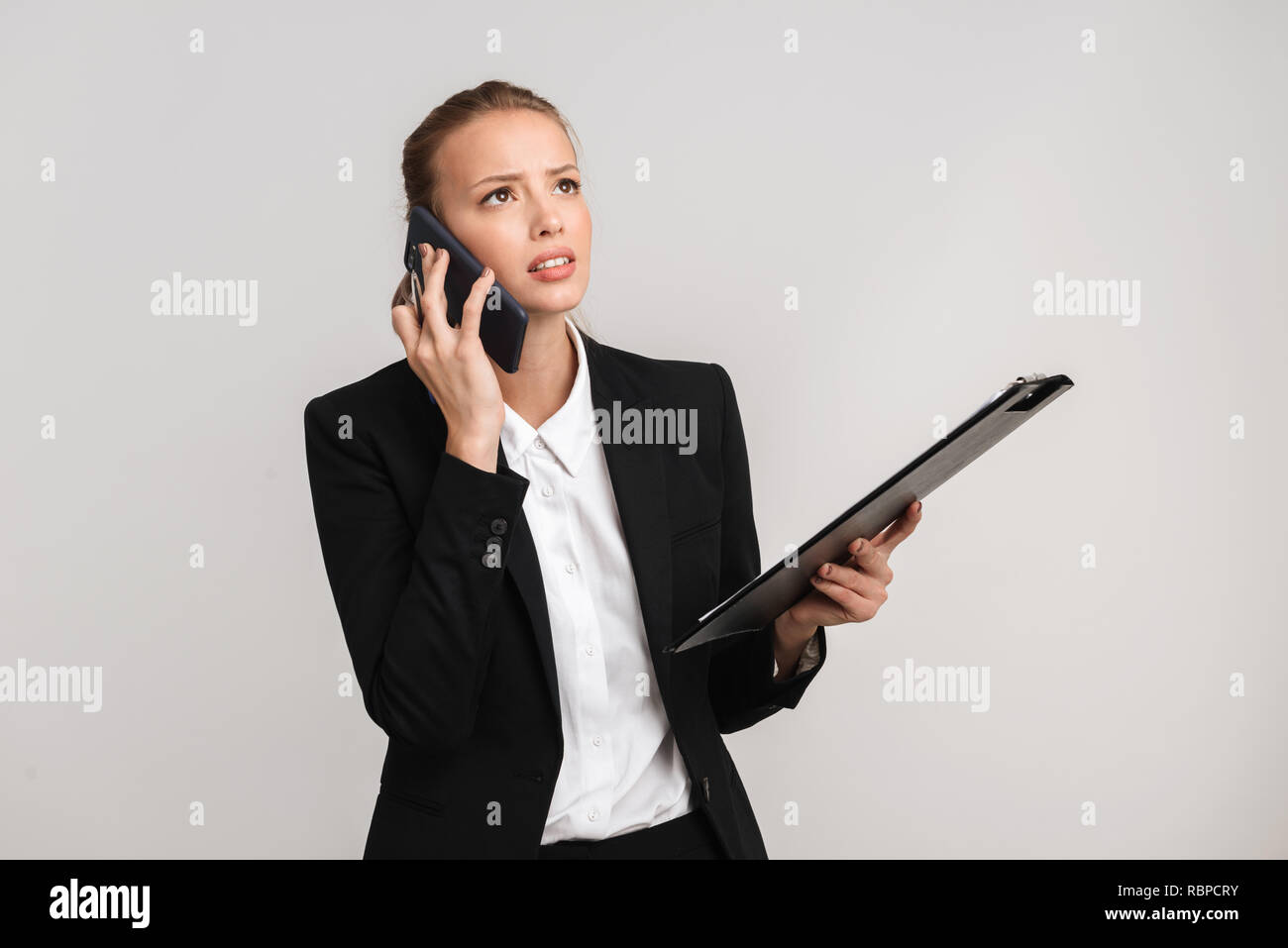 Upset blonde business woman standing isolated over gray background ...