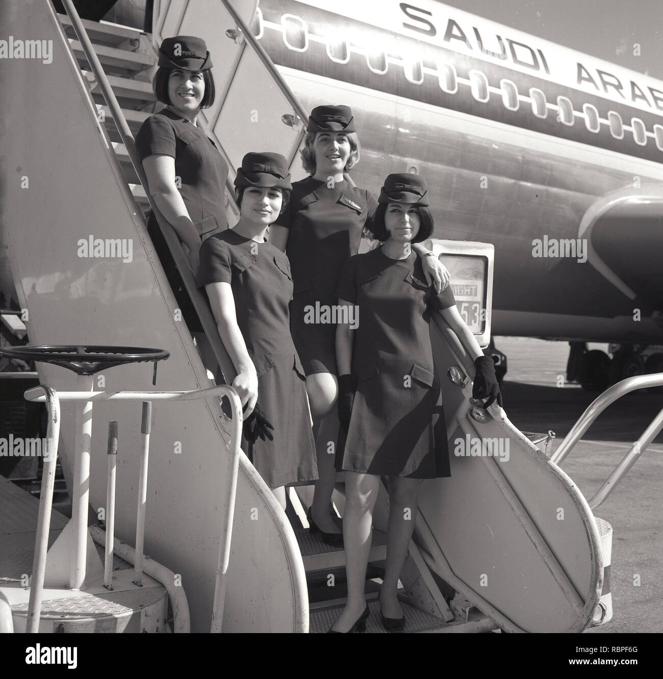 1960s, historical, female air hostesses of Saudi Arabian Airlines standing outside on the boarding stairs to the aircraft. Stock Photo