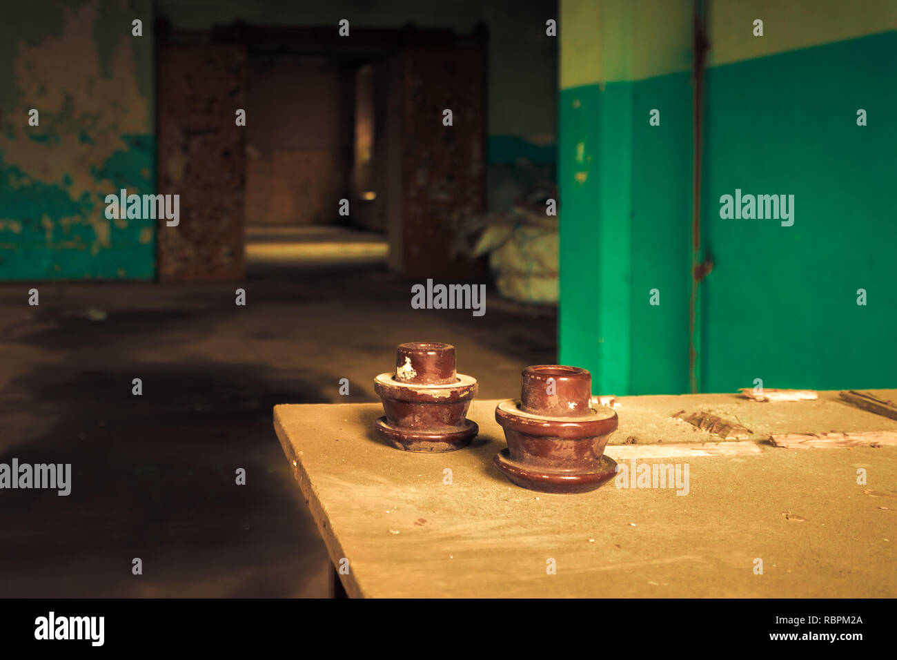 Electrical insulator on table inside abandoned old factory building. Stock Photo