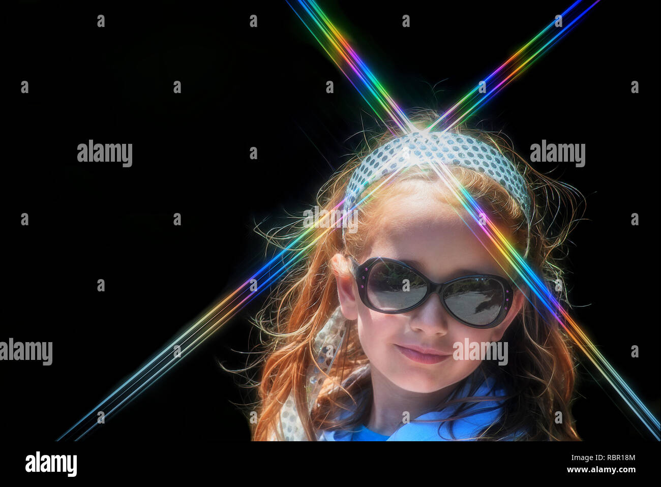 A little girl wearing sunglasses poses for a portrait wearing a sparkly headband that refracts rainbow light. Stock Photo