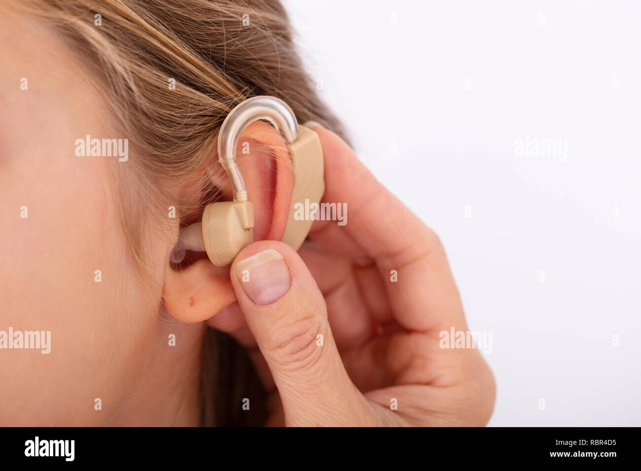 Close-up Of A Doctor Hand Inserting Hearing Aid In Girl's Ear Stock Photo