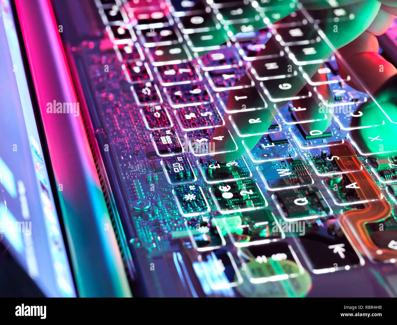 Double exposure of a man typing at a laptop computer keyboard exposing the electronics underneath. Stock Photo