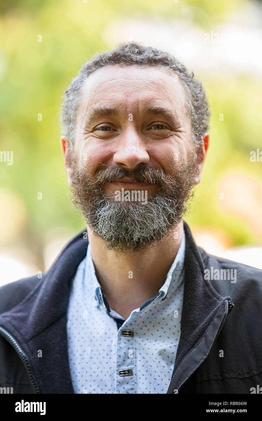 Portrait Of Handsome 40 Year Old Man With Curly Hair And Grizzled Stock Photo Alamy