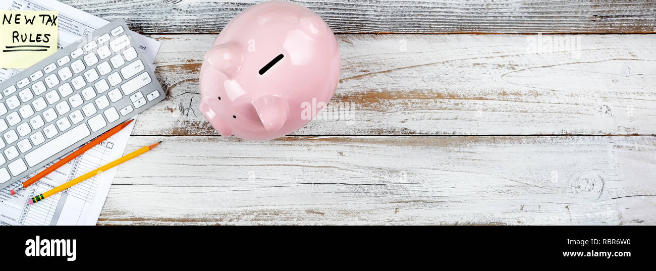 Income tax forms with new rule changes and piggy bank on white rustic desk Stock Photo