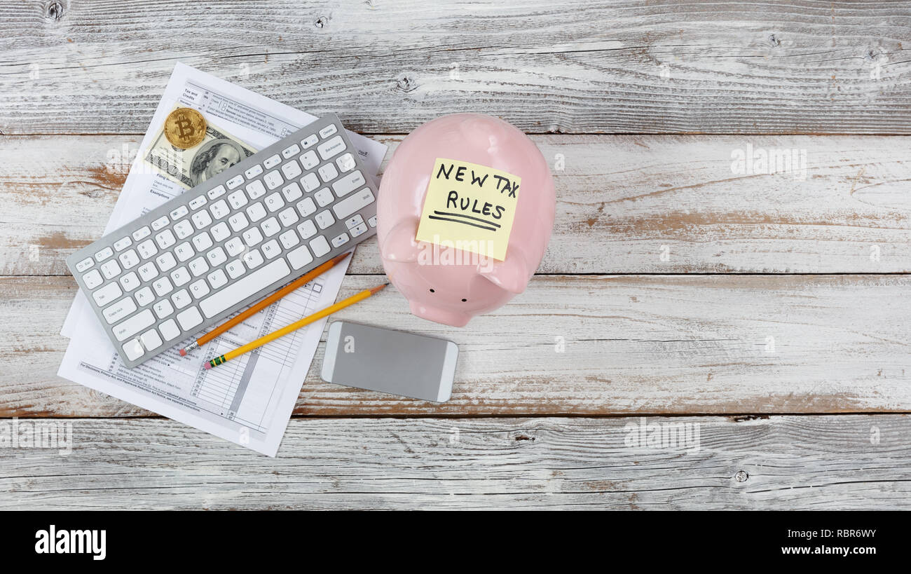 Overhead view of income tax forms with new rule changes and piggy bank on white rustic desk Stock Photo