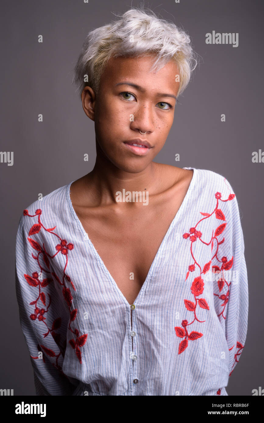 Young beautiful rebellious woman with short hair against gray ba Stock Photo