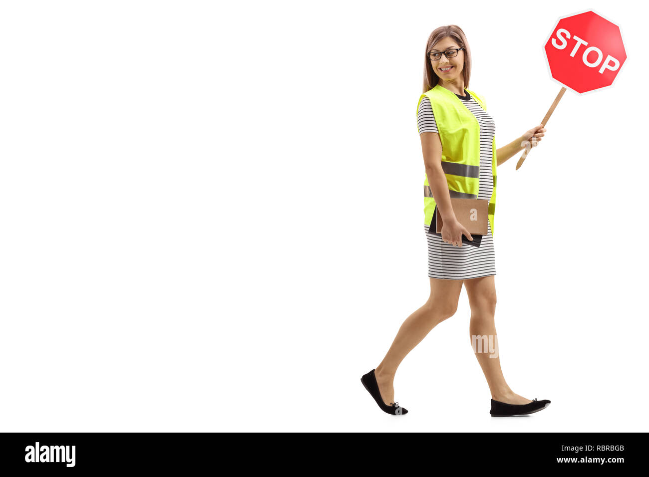 Full length shot of a young woman with safety vest and stop sign walking and looking backwards isolated on white background Stock Photo