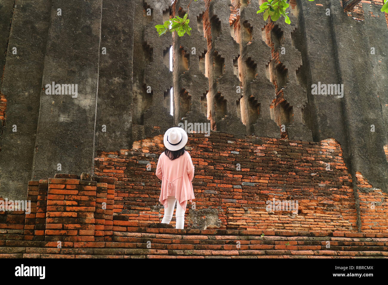 Female Tourist Looking at False Windows of the Royal Vihara at Wat Mahathat Temple within Ayutthaya Historical Park, Archaeological site in Thailand Stock Photo