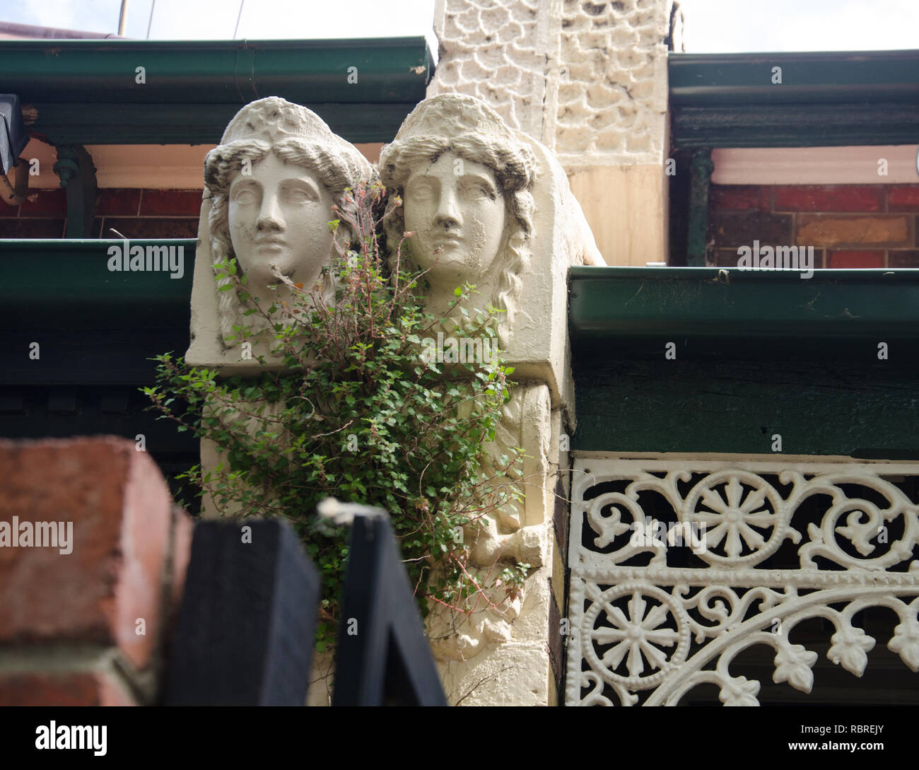 Enigmaticsculpted heads adorn the exterior of a tiny house in Melbourne's Fitroy neighbourhood where several streets are lined with small houses Stock Photo
