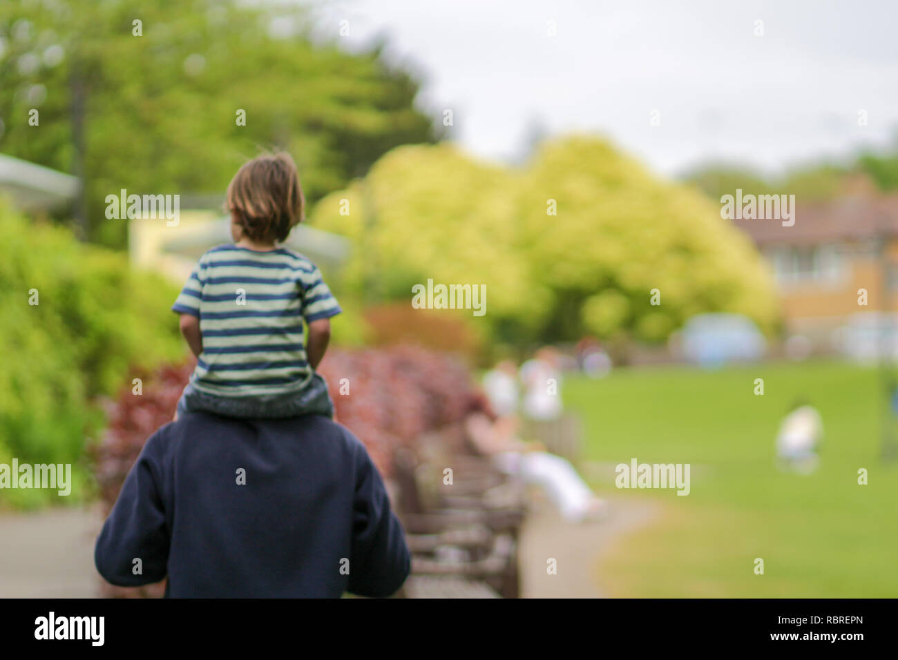 Happy family concept - blurred picture of the child who sits on father neck and having fun in park on sunny day Stock Photo
