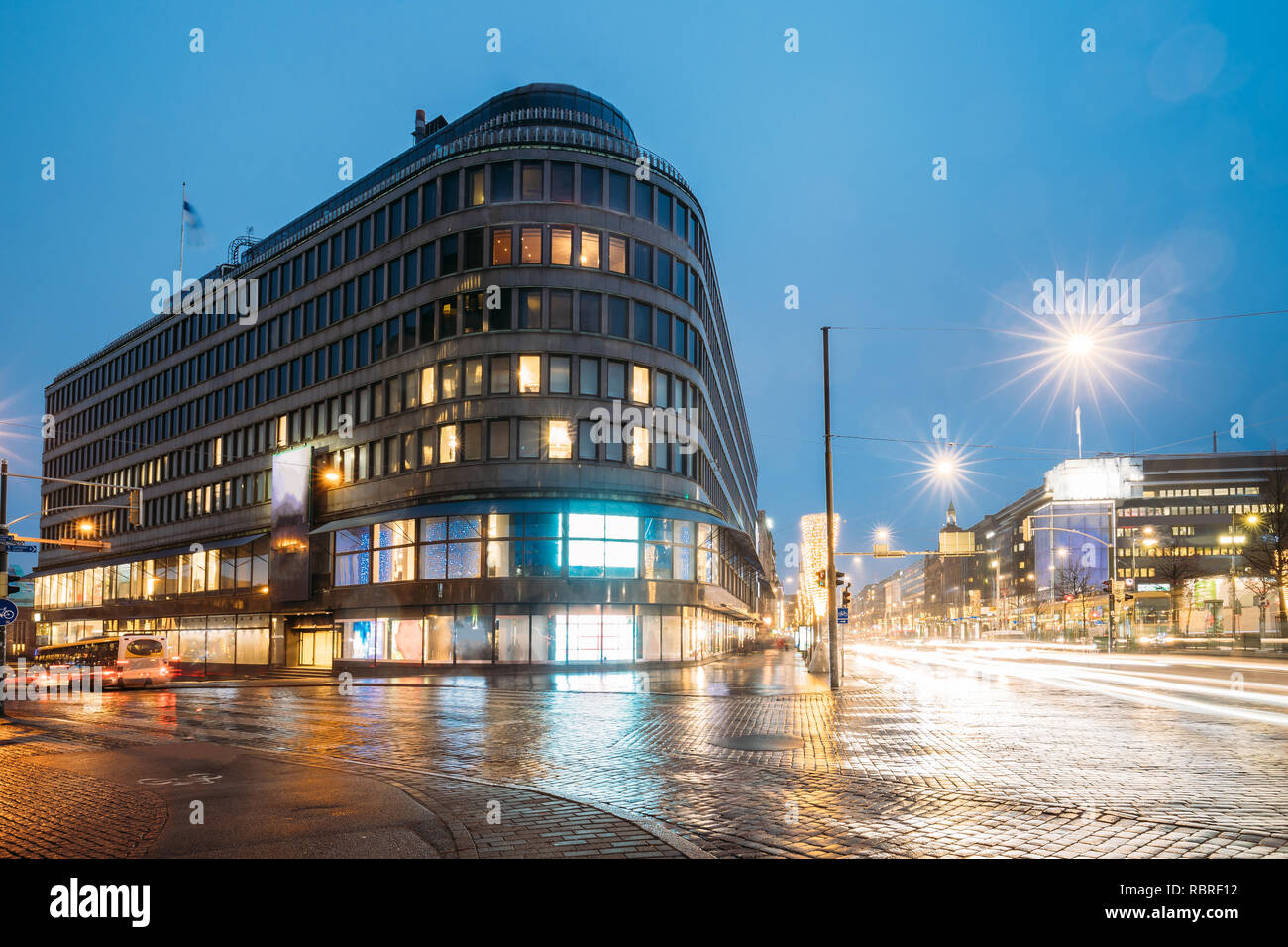 Helsinki, Finland. Hotel And Shopping Center On Crossroad Of Kaivokatu Street And Mannerheimintie Or Mannerheim Avenue In Evening Or Night Illuminatio Stock Photo