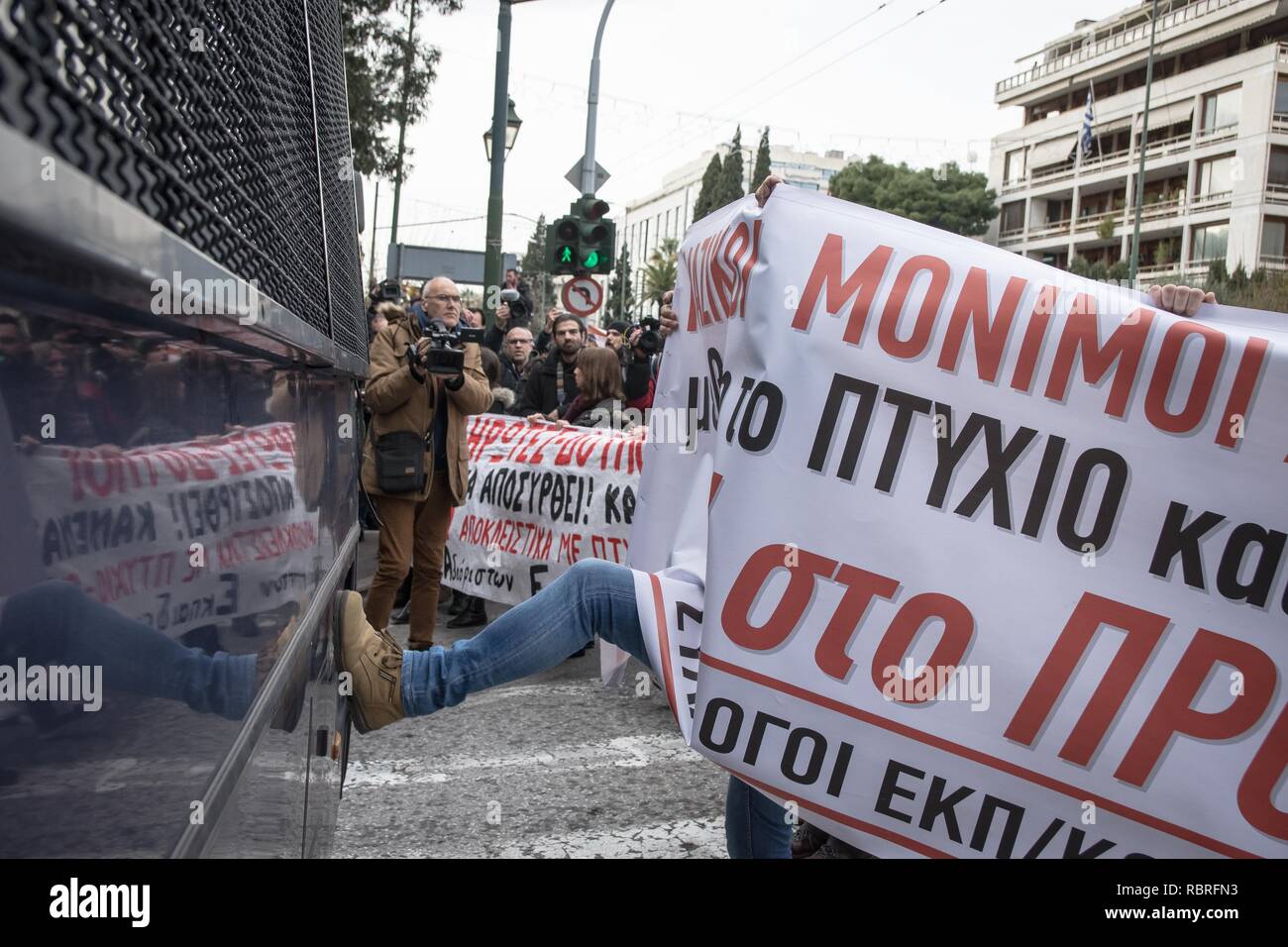 A protester seen holding a banner while kicking a police bus during the demonstration. Thousands of people protest to withdraw the Ministry of Education's plan on the new system of the 15,000 recruits. Stock Photo