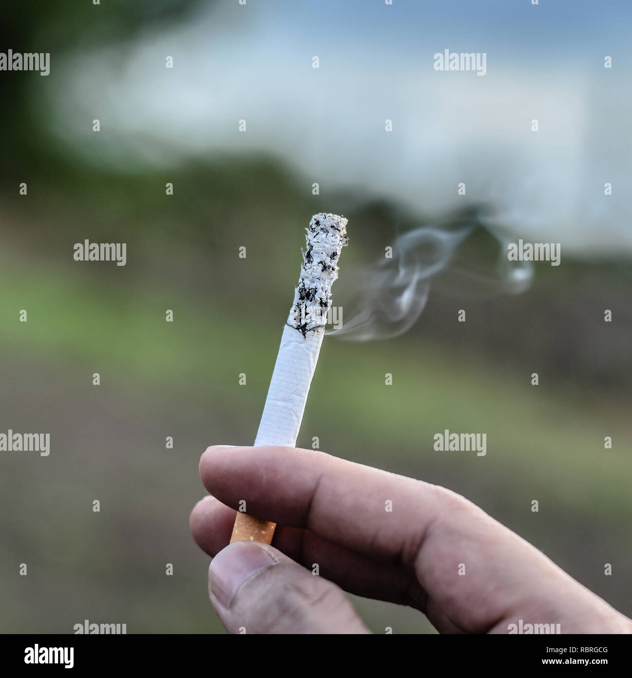 Cigarette in hand / cigarette smoke burning on hand man smoking on