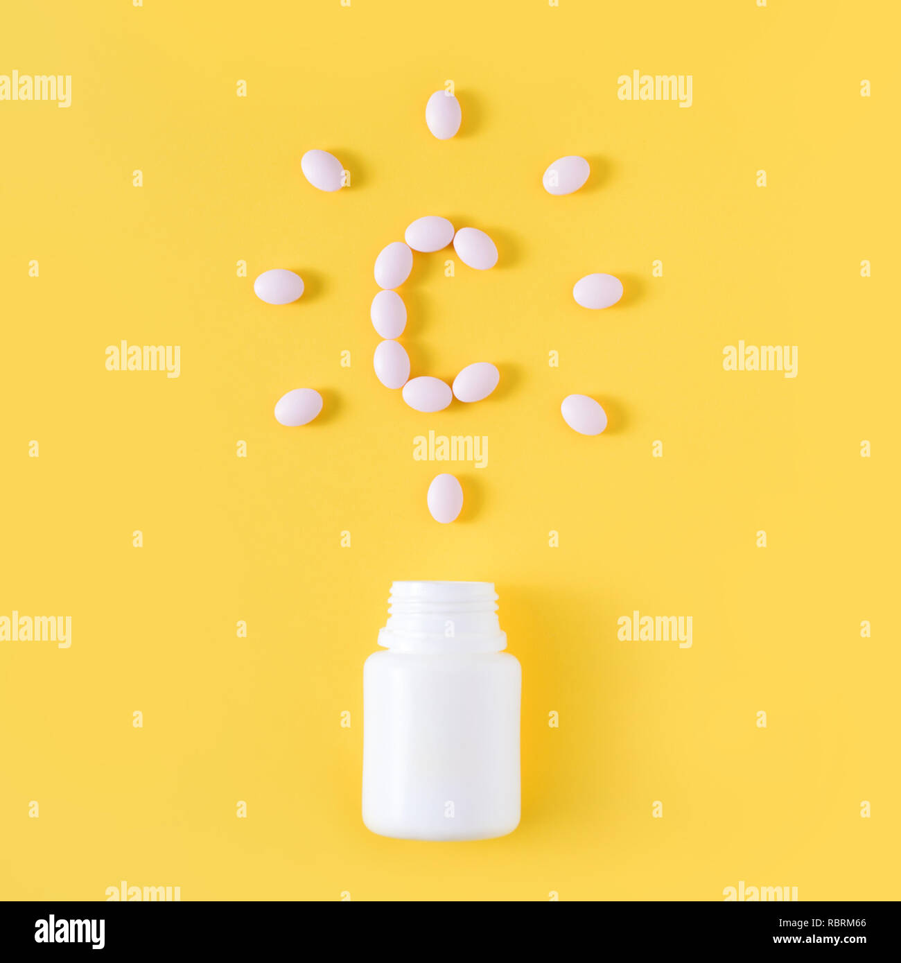 Vitamin c pills dropped from bottle on yellow background. Flat lay, top view. Stock Photo
