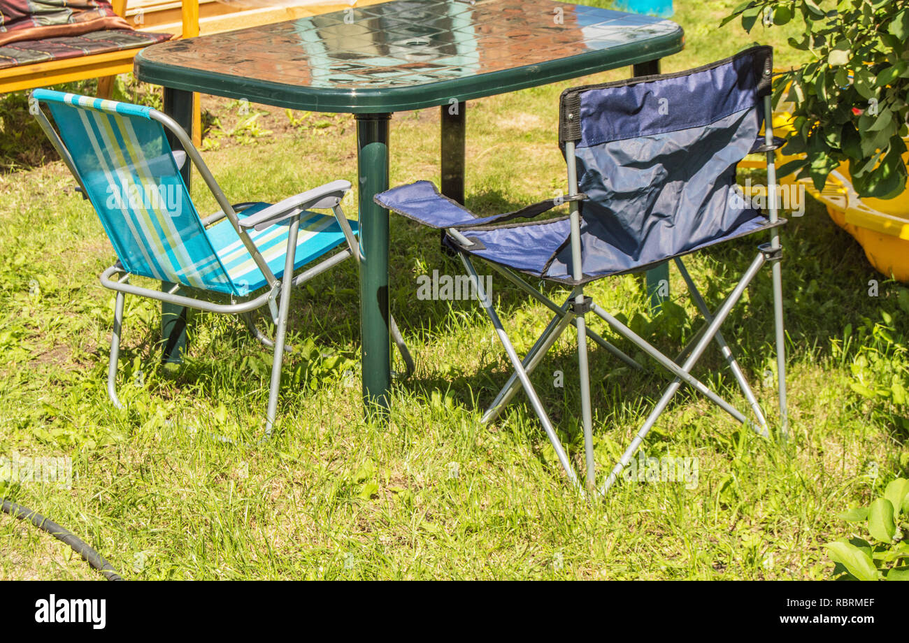 Plastic folding table and folding chairs for camping stand on the grass