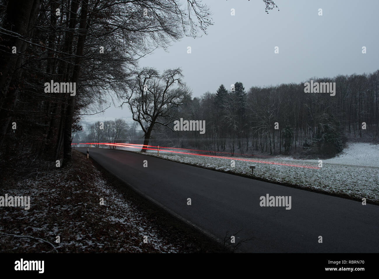 wintry road with light trails from cars Stock Photo