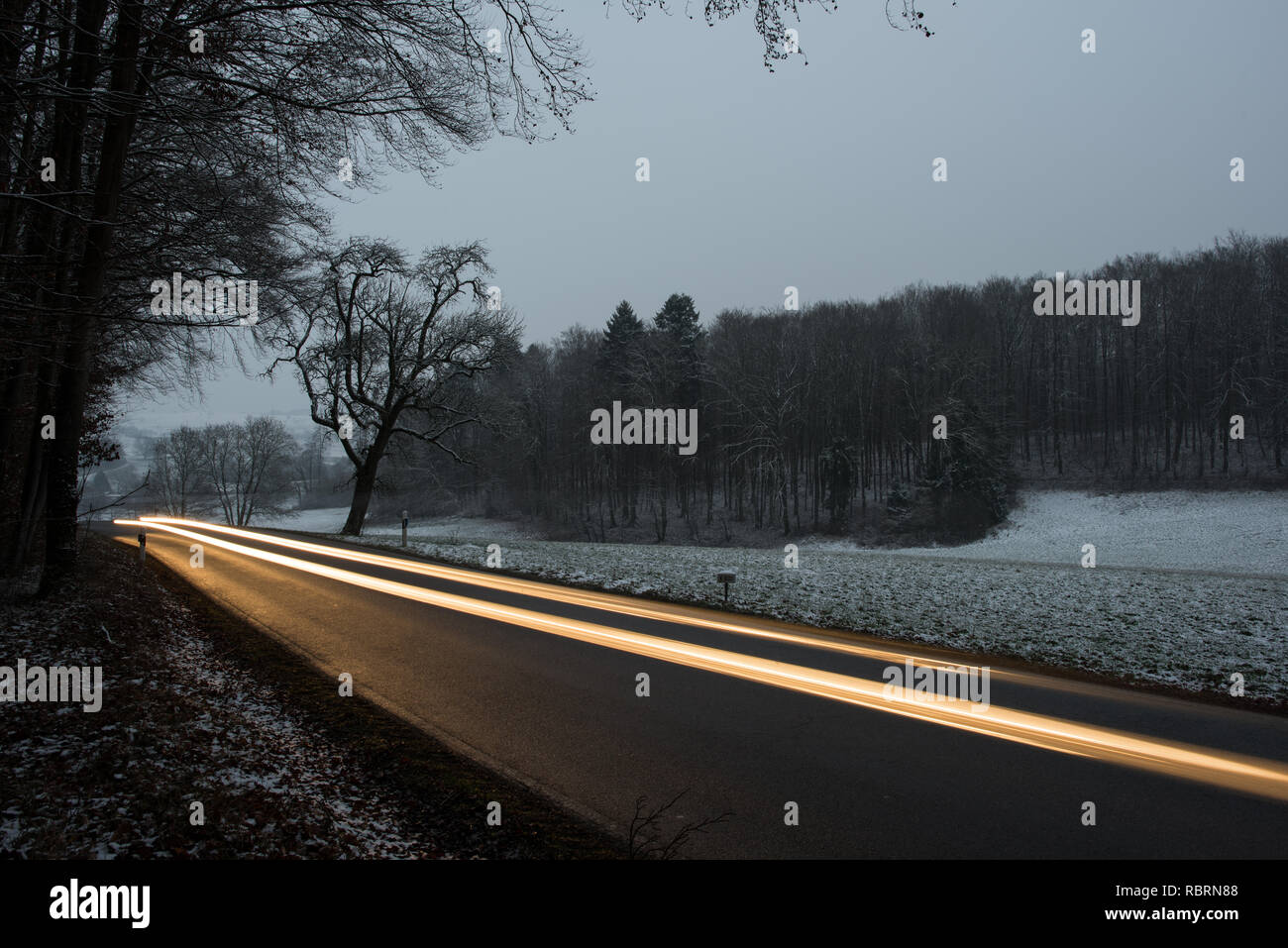 wintry road with light trails from cars Stock Photo