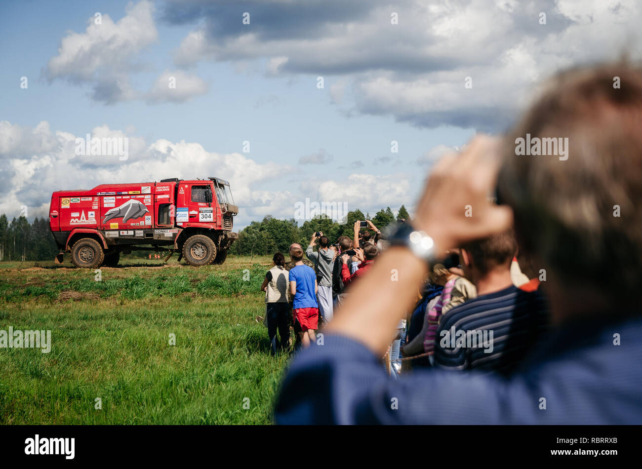 Polack, Belarus - May 31, 2015: Spectators watch Belarusian MAZ Racing Team DAKAR Truck drive across field in Baja Rally in Belarus. Stock Photo