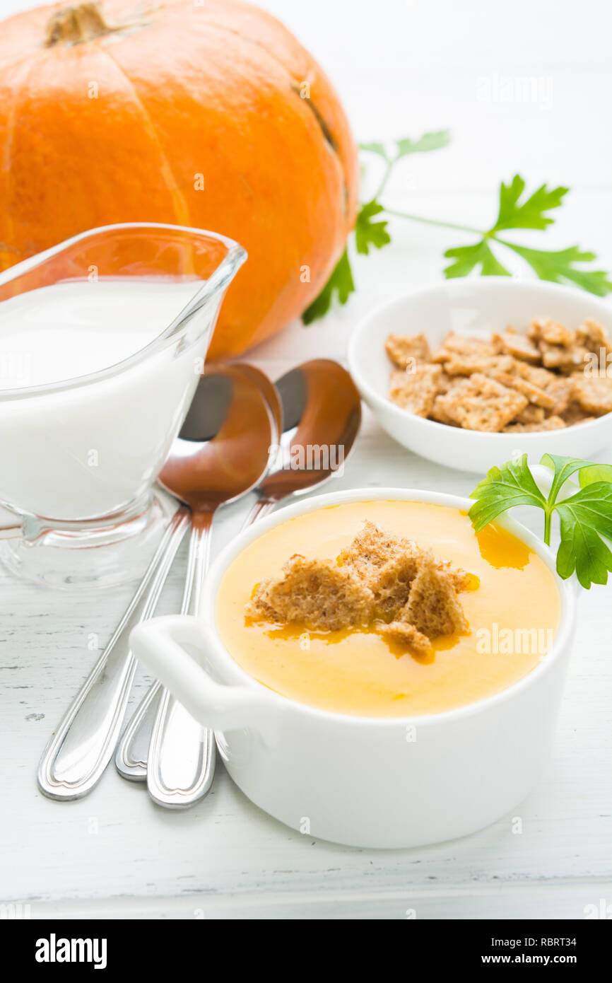 Pumpkin soup with crutons on white wooden table, vertical shot Stock Photo