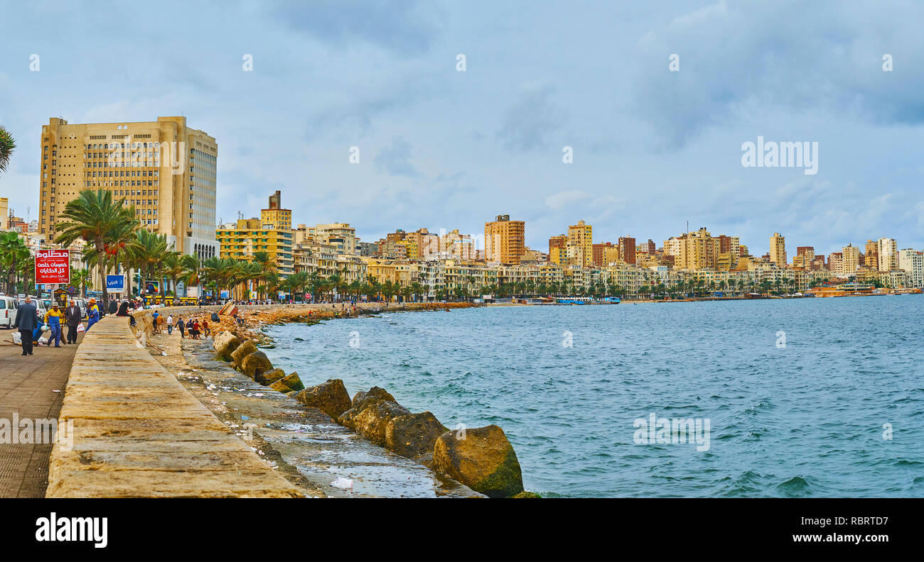 ALEXANDRIA, EGYPT - DECEMBER 19, 2017: Walk along the shore of the city with a view on urban quarters and line of palms, on December 19 in Alexandria. Stock Photo