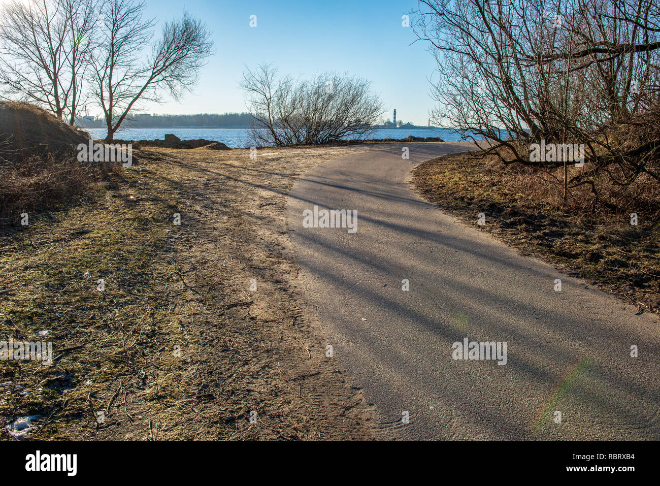 empty asphalt road in winter with shadows from forest trees and snow ...