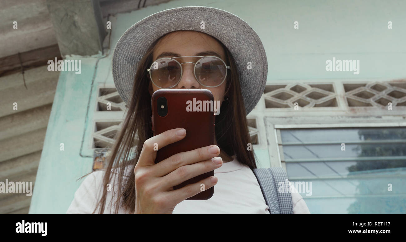 Stylish female using smartphone near shabby building Stock Photo