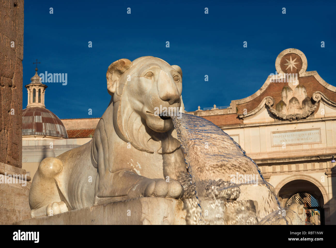 Marble egyptian lion from People Square central fountain with city wall ancient gate, in the background, in the center of Rome (erected in 1823) Stock Photo