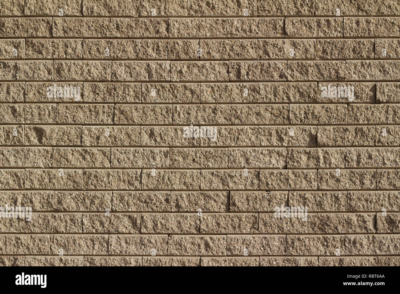 Light brown tan colored rough textured stone brick wall abstract background Stock Photo