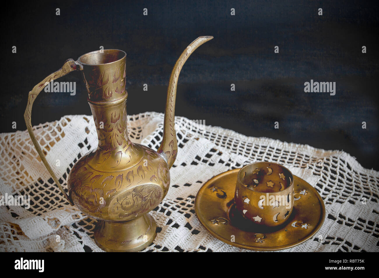 A copper pot for liquids and a copper candleholder on hand-knit lace. Handmade. Ancient items. Stock Photo