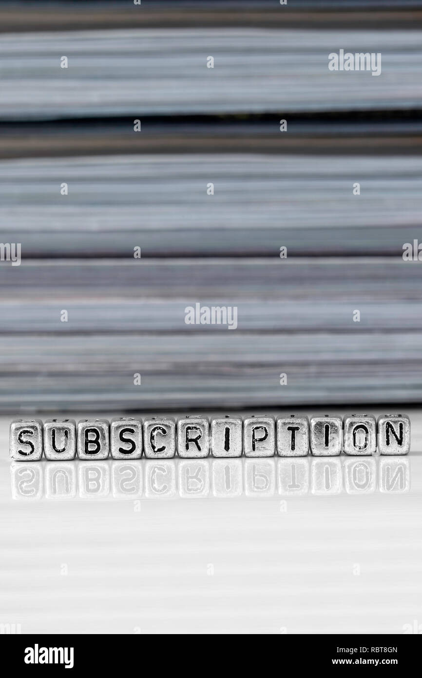 Subscription on beads with magazines stacked in the background reflected on a white surface Stock Photo