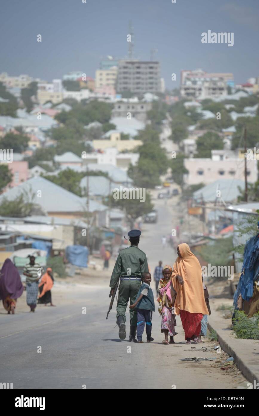 A member of the Somali Police Force walks down a road in Mogadishu with his son on December 21. AU UN IST PHOTO - Tobin Jones (11511062233). Stock Photo