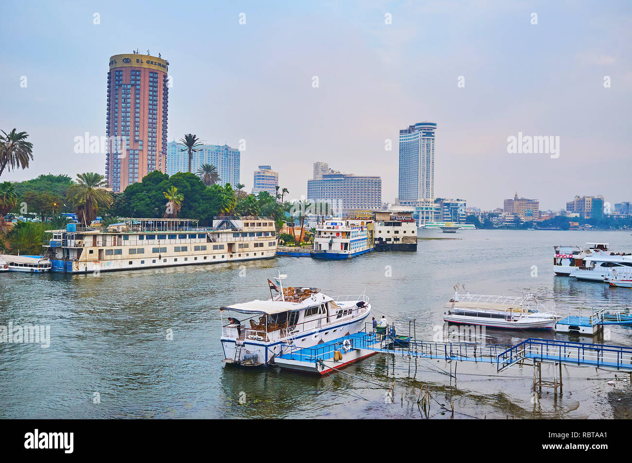 GIZA, EGYPT - DECEMBER 19, 2017: The tourist boats, floating restaurants and cruise ships are moored at the banks of Giza and Gezira Island on Nile ri Stock Photo