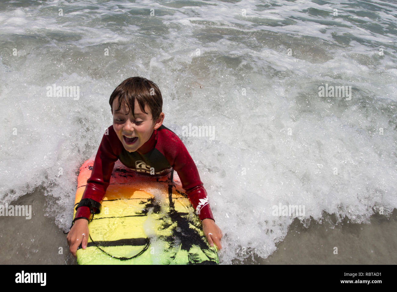 Young boy bodyboarding in the shallow waves Stock Photo