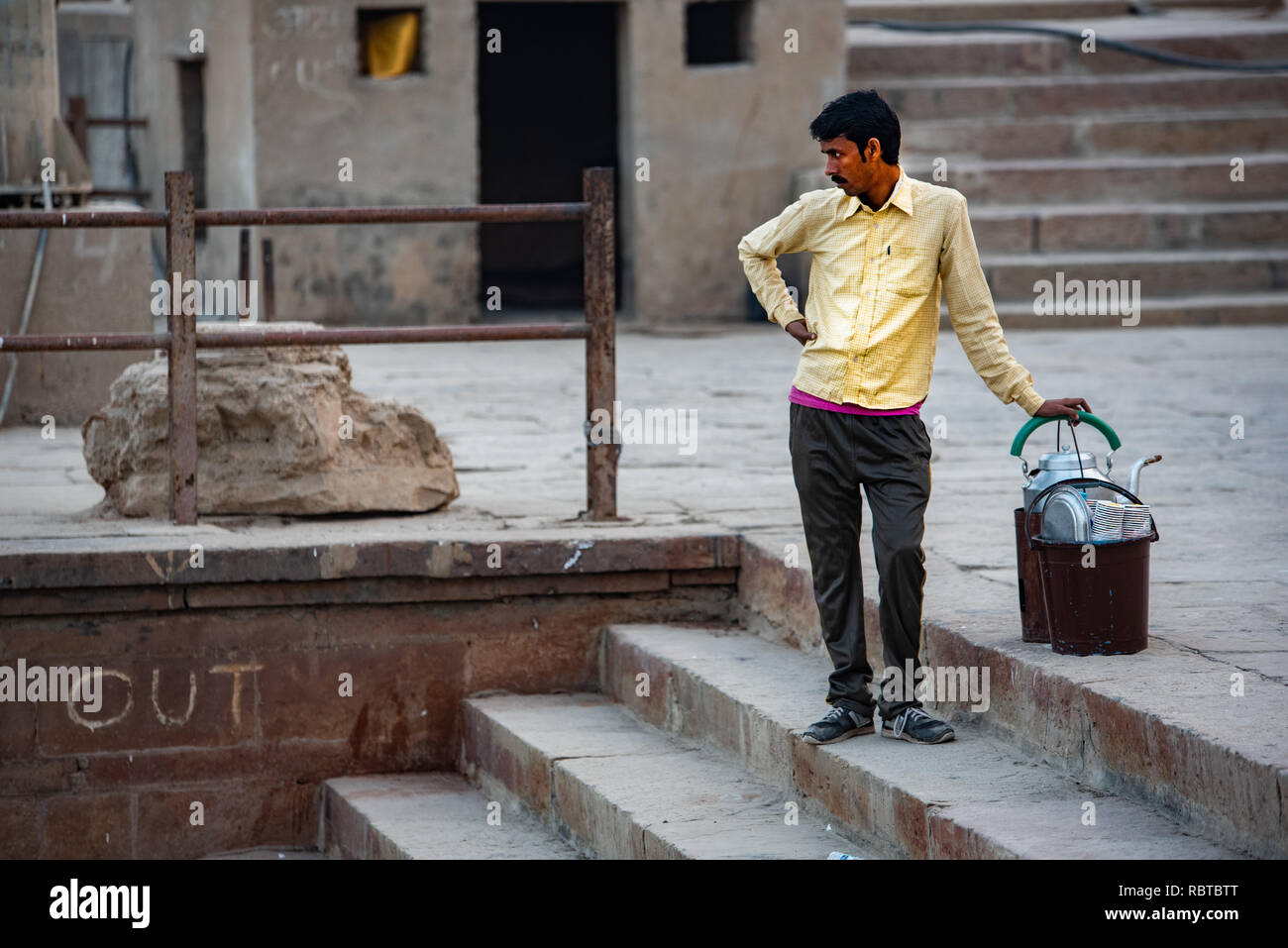 A Chaiwala or Tea-Seller standing on the Ghat in Varanasi looking at the river Ganges at the arriving boats to survey sales opportunities. Stock Photo