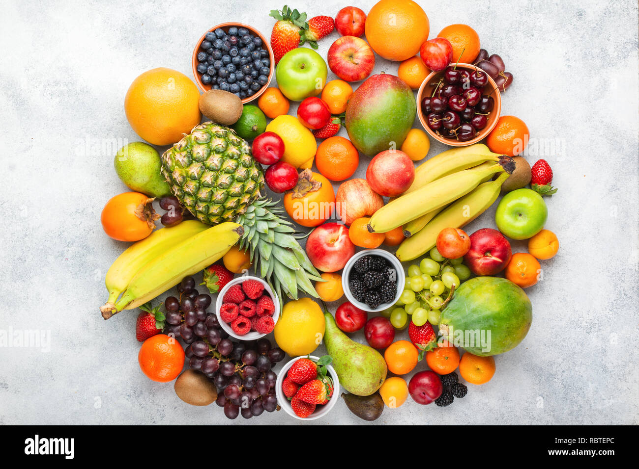 Circle made of healthy colorful fruits, strawberries raspberries oranges plums apples kiwis