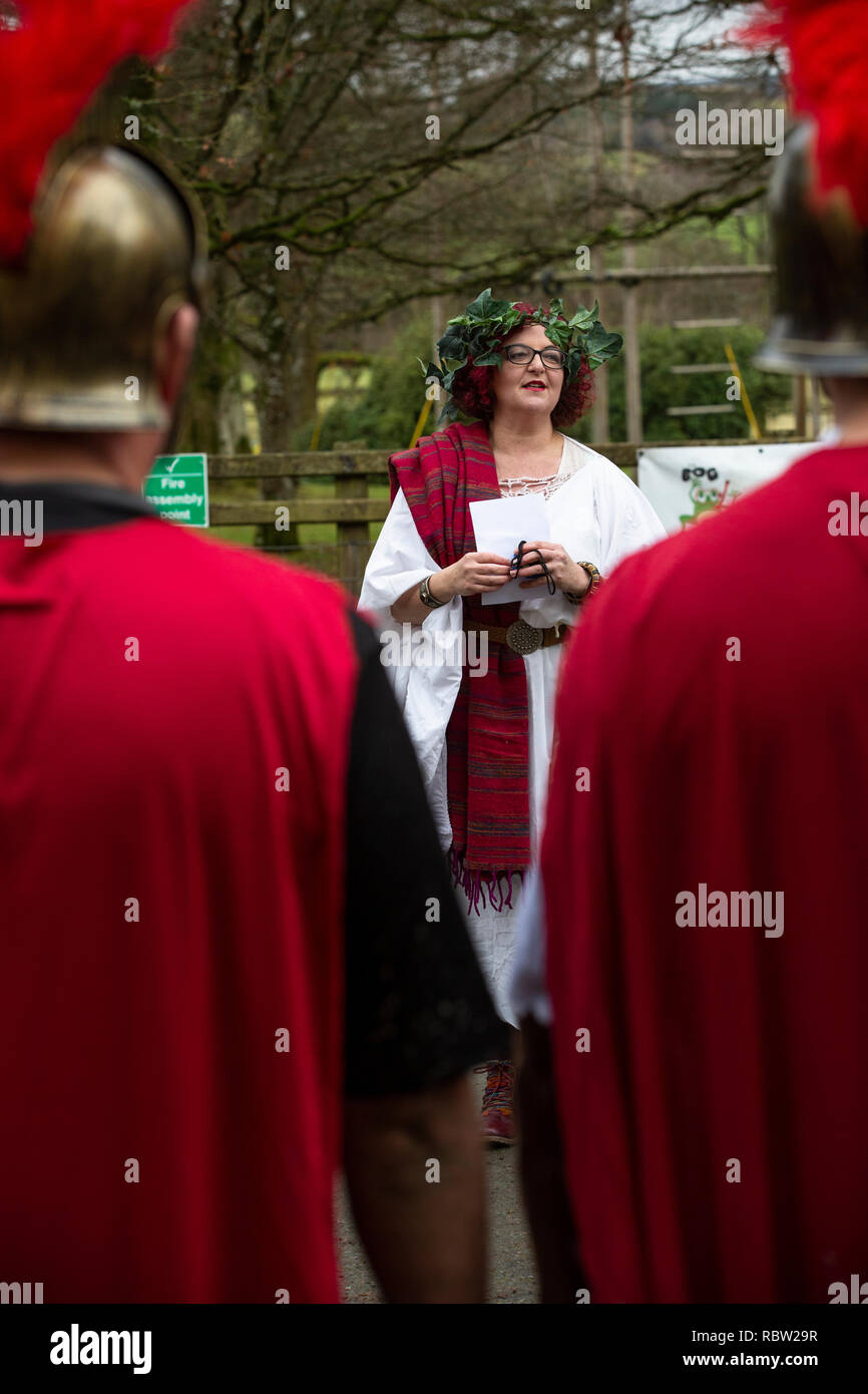 A woman in a Roman fancy dress toga addresses competitors before a mountain bike chariot race in the annual Llanwrtyd Wells World Mountain Bike Chariot Race in Powys, Wales. Stock Photo