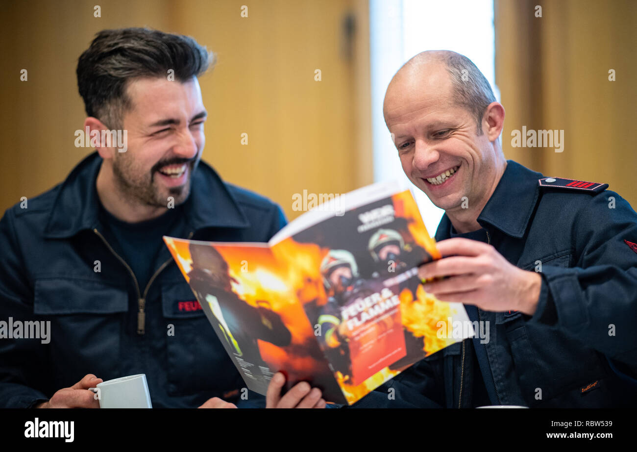 10 January 2019, North Rhine-Westphalia, Gelsenkirchen: The firemen Philip (l) and Hacki sit in the lounge of the fire station in Gelsenkirchen and browse through the WDR magazine of the Feuer & Flamme series. After the great success of the first season, which ran on WDR television in mid-2017 and was nominated for the German Television Prize, the documentary series will be continued on WDR television from 21 January to 25 March 2019, Monday from 8.15 p.m. The production effort was enormous: 70 days in a row, 24 hours a day the 20-man TV crew shot. During the missions, up to 57 special cameras Stock Photo