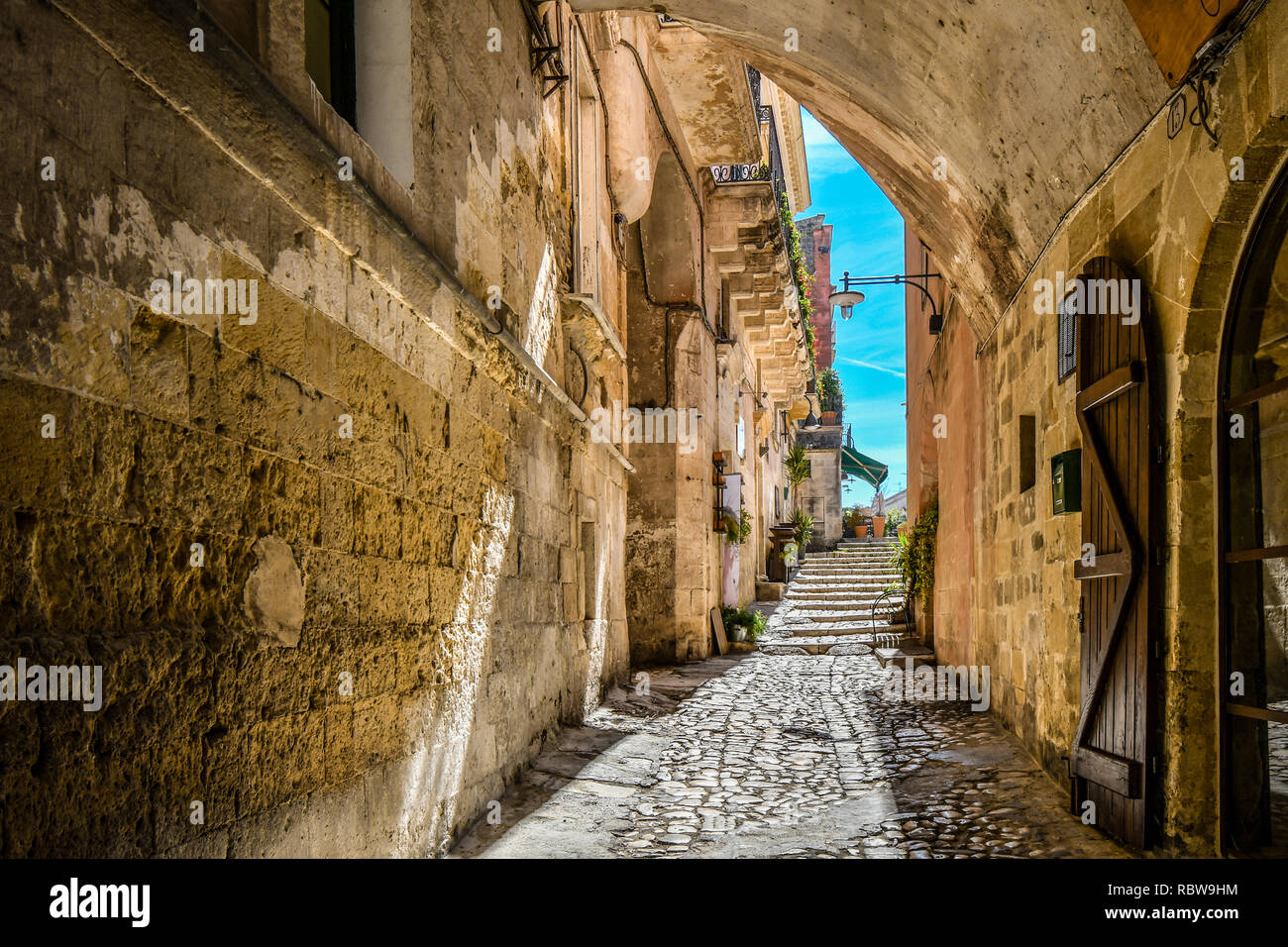 A covered alley leads to a cafe and piazza in the ancient city of Matera, Italy Stock Photo