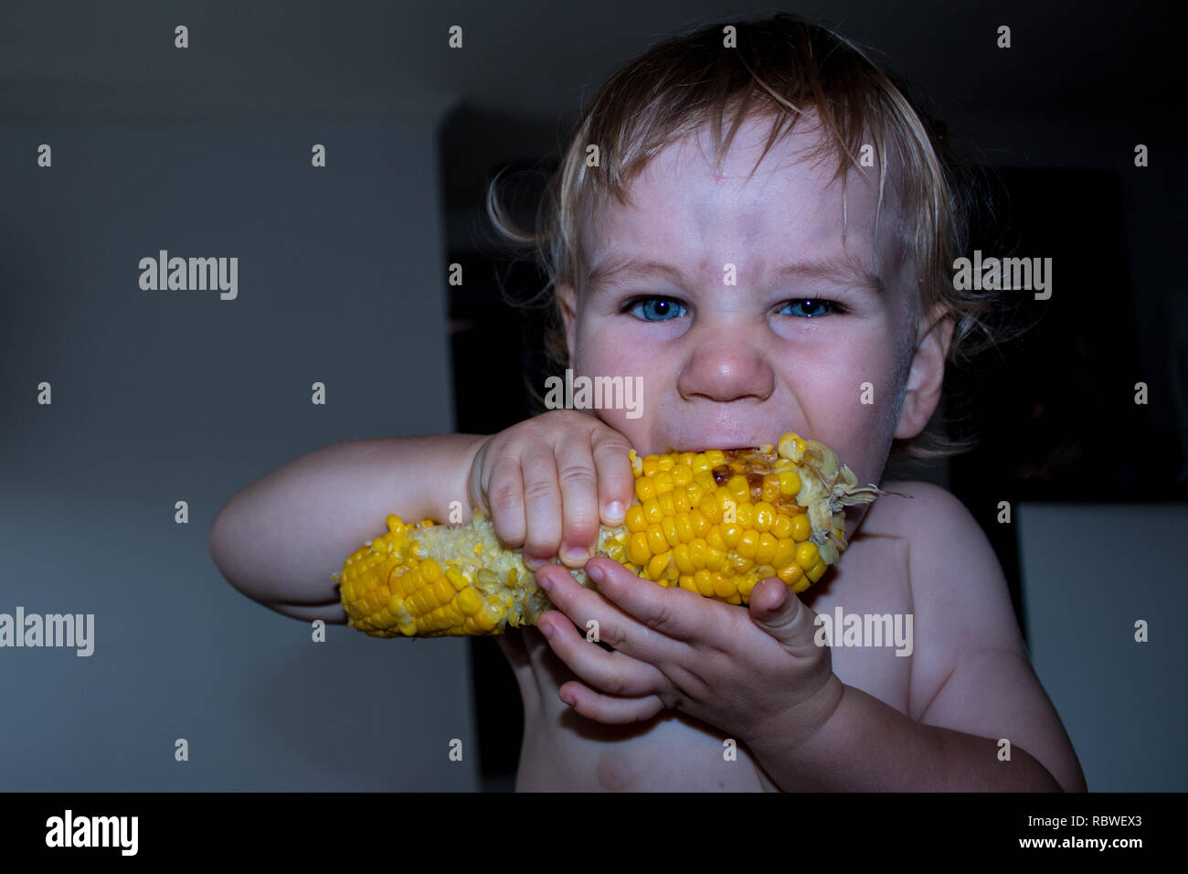 A photo of a little boy eating and enjoying maize (corn) Stock Photo