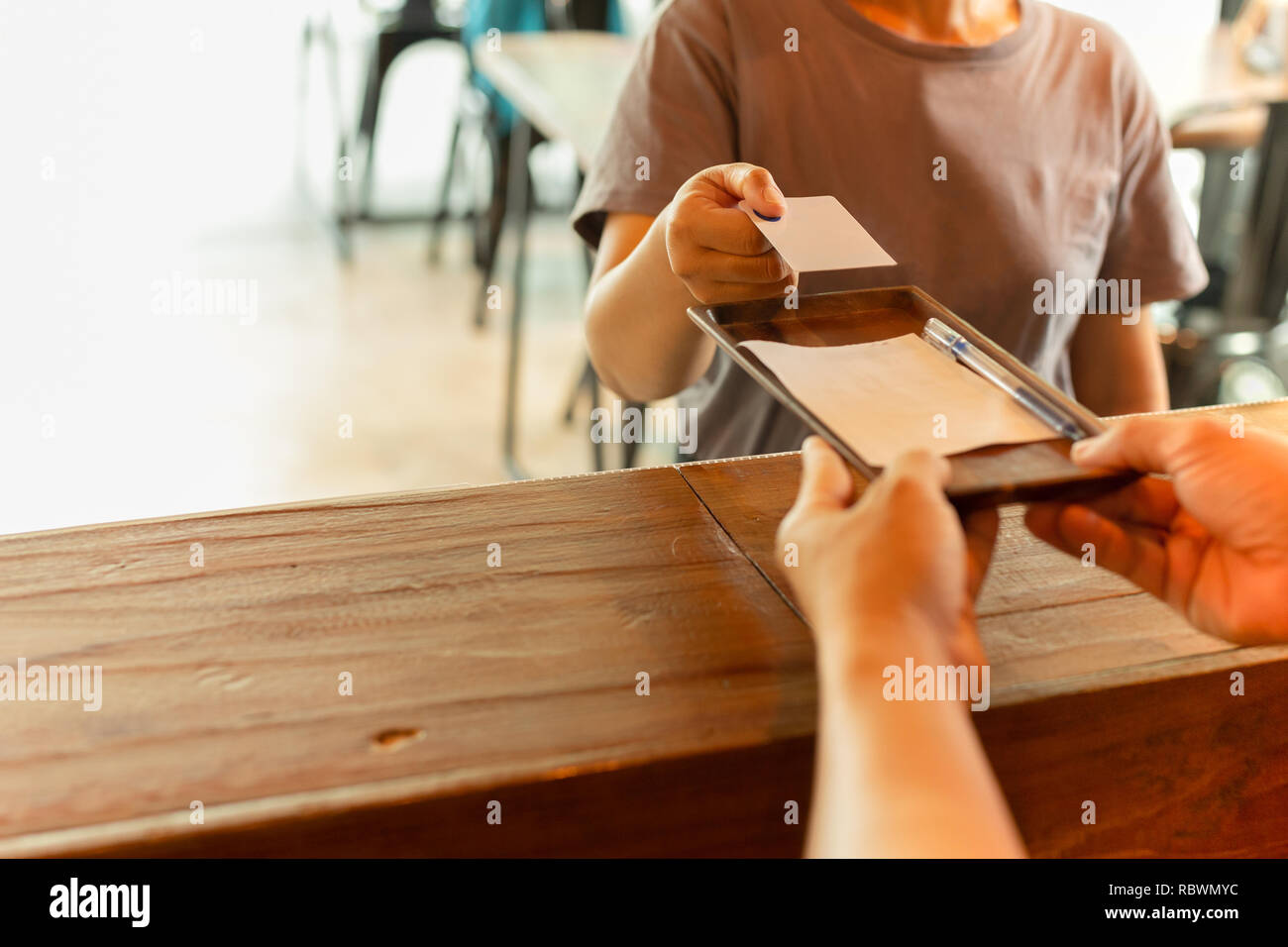 Male waiter serving coffee with laptop and glasses on working table in cafe. Stock Photo