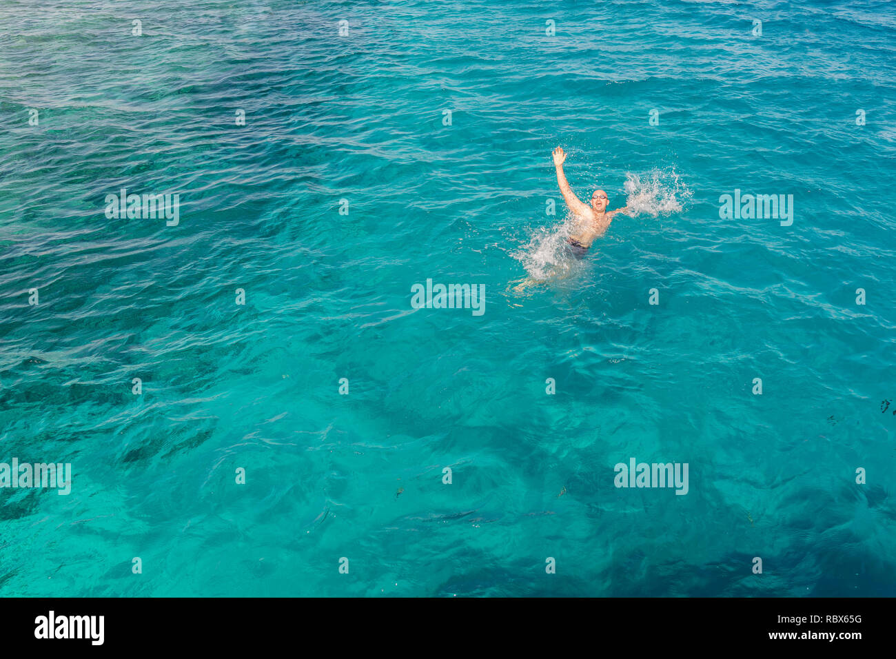 Drowning man in sea asking for help with raised arms. The man is