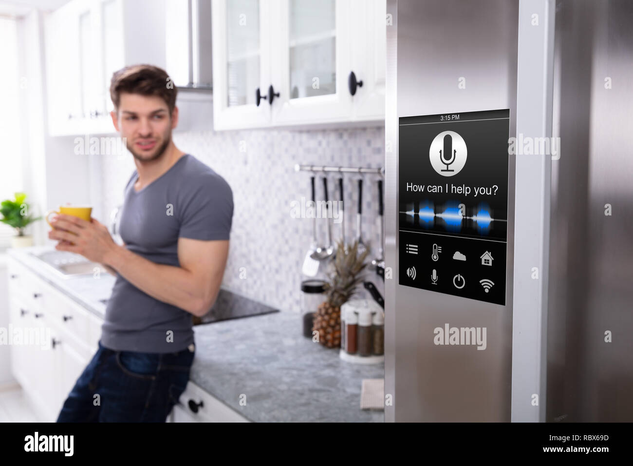 Man Standing Near Oven With Voice Recognition Function In Kitchen Stock Photo