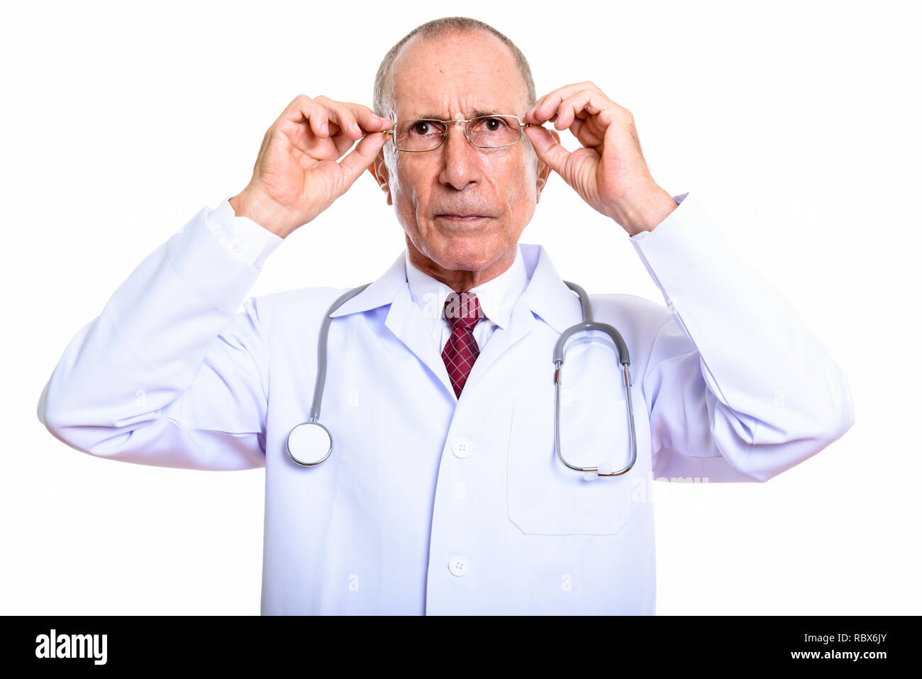 Studio shot of senior man doctor holding eyeglasses with both ha Stock Photo