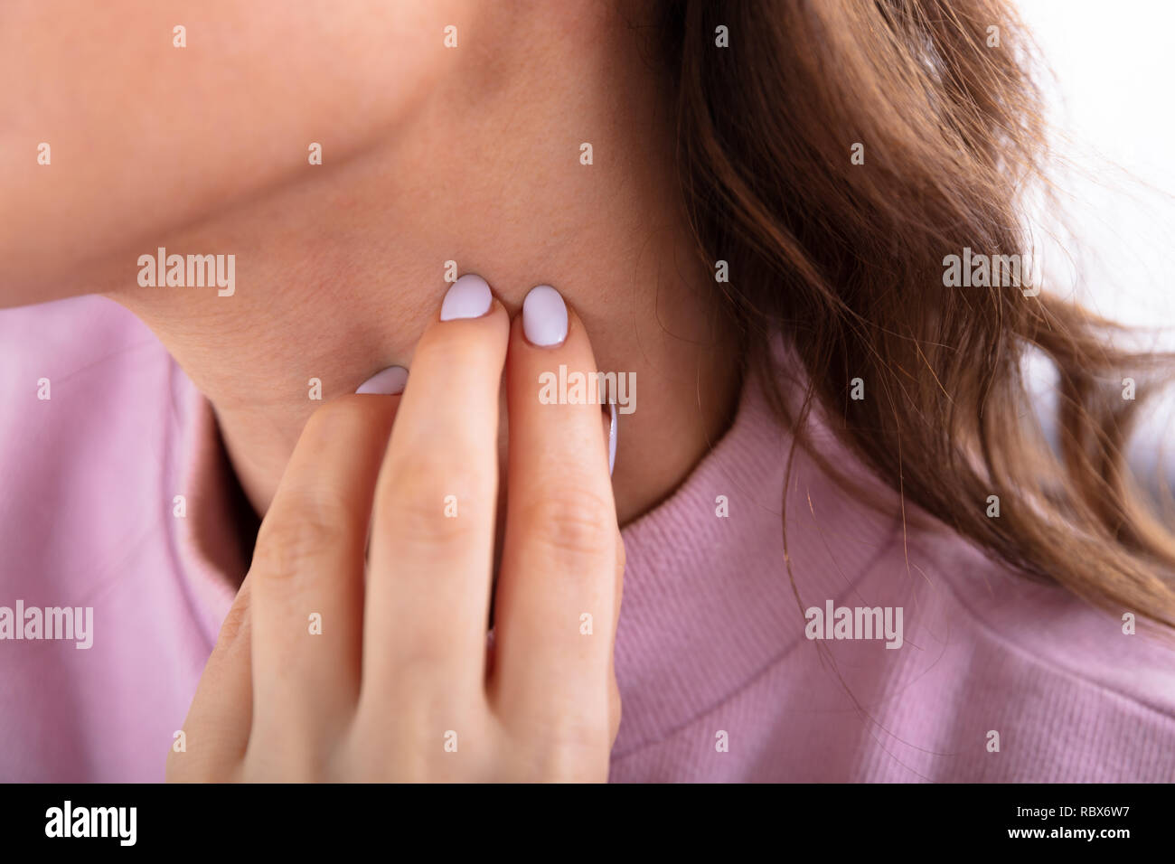 Close-up Of A Woman's Hand Scratching Her Neck Stock Photo