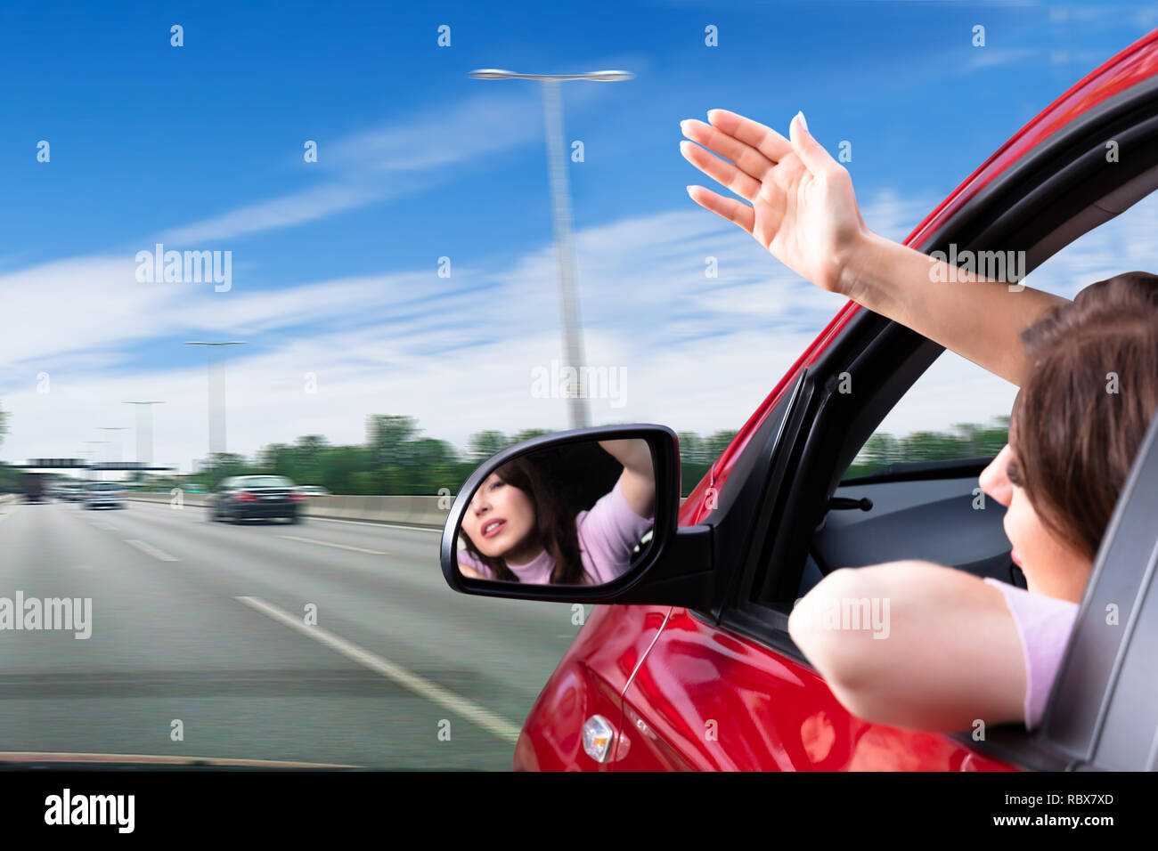 Young Woman Making Gesture While Looking Out Of Car Window Stock Photo