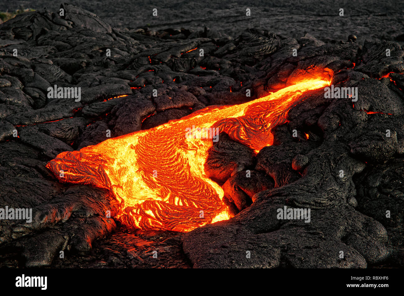 Hot magma escapes from an earth crevice as part of an active lava flow, the glowing lava slowly cools and freezes - Location: Hawaii, Big Island, volc Stock Photo