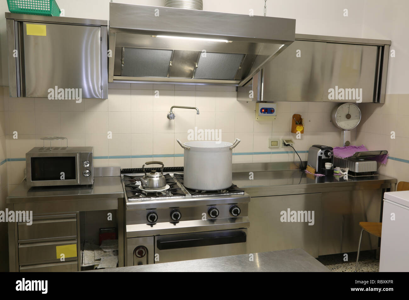 https://c8.alamy.com/comp/RBXKFR/stainless-steel-furniture-of-a-large-industrial-kitchen-with-a-large-saucepan-on-the-stove-and-the-table-for-food-preparation-RBXKFR.jpg