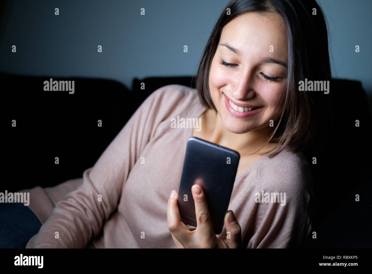 Cheerful girl watching the smart phone display at night , main focus on
